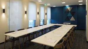 Ett konferensrum med långa bord, stolar och en blå accentvägg.