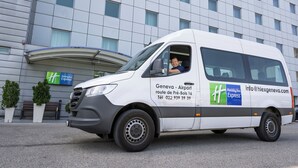 A white van parked in front of a building with a Holiday Inn Express sign. - Holiday Inn Express Geneva Airport by IHG (Meyrin)