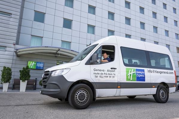 Un fourgon blanc était garé devant un immeuble sur lequel on pouvait voir une enseigne « Holiday Inn Express ».