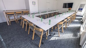 A conference room with a long table, chairs, and water bottles. - Holiday Inn Express Geneva Airport by IHG (Meyrin)