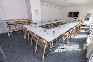 Konferenssihuone, jossa on pitkä pöytä, tuoleja ja vesipulloja.