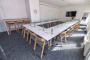 Un salón de conferencias con una larga mesa, sillas y botellas de agua.