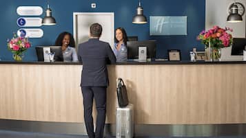 Mostrador de recepción de hotel con pantalla digital, un reloj y el letrero de Holiday Inn Express.