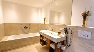 Un baño moderno con bañera, dos lavamanos, tocador y un espejo grande.