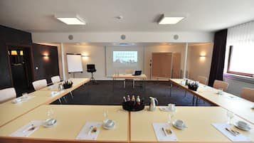 A conference room with a long table, chairs, a projector screen, and a whiteboard.