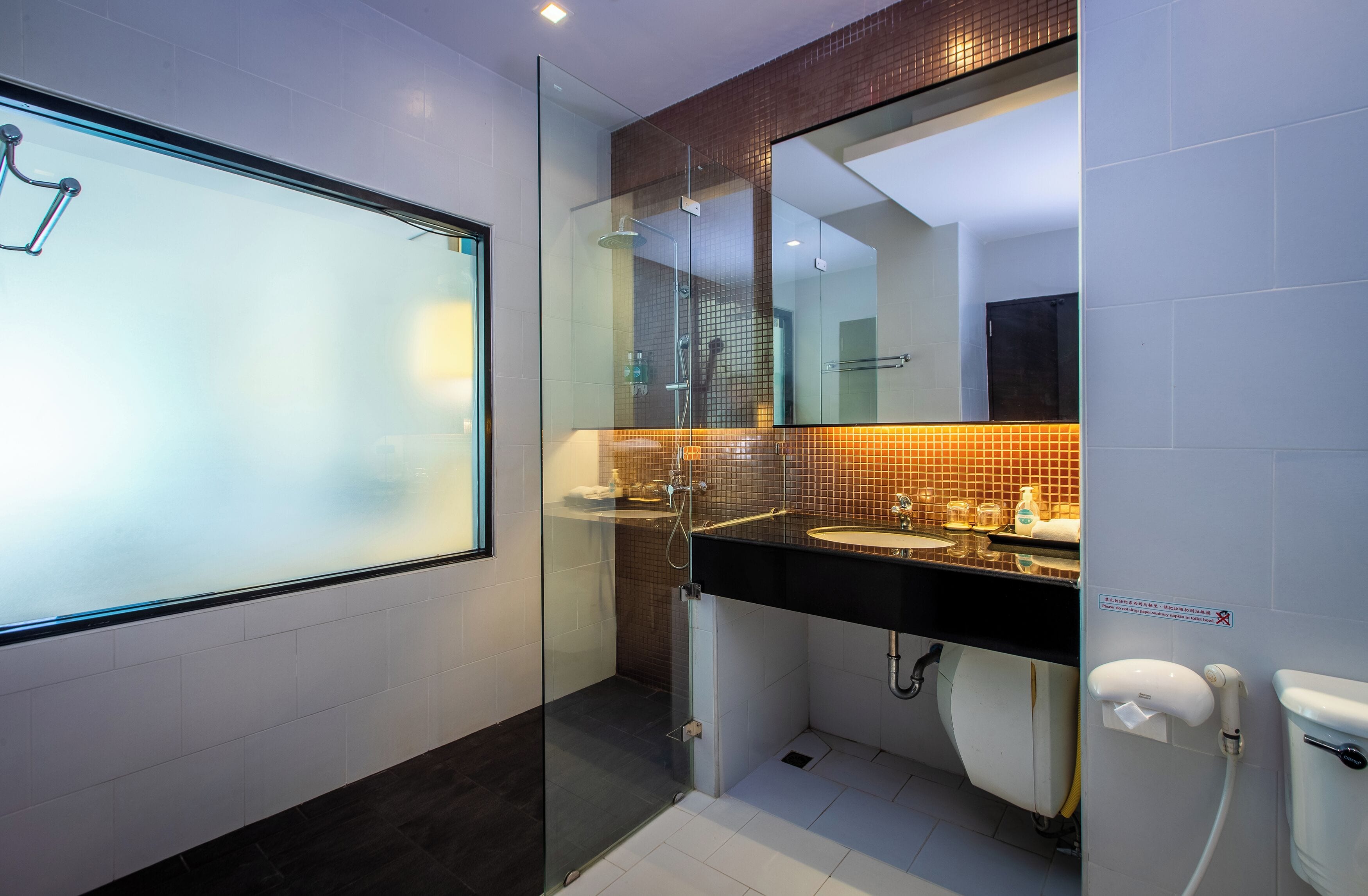 A modern bathroom with a glass shower enclosure, a black countertop sink, and a large mirror above the sink.