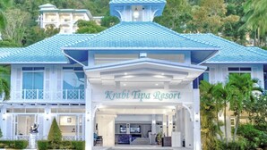 Un resort con una entrada destacada, un techo azul y abundante vegetación a su alrededor.
