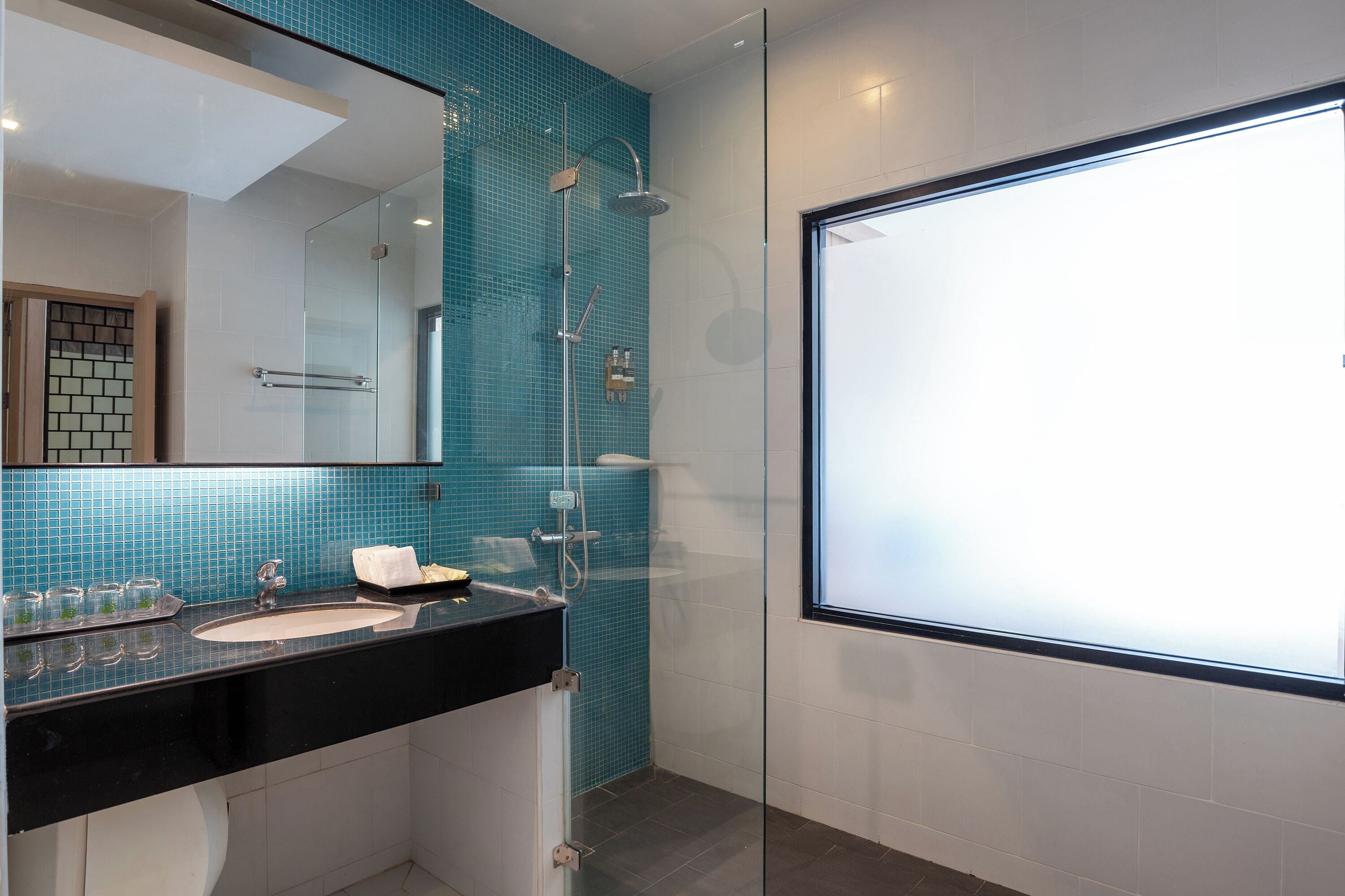 Een moderne badkamer met een douchecabine van glas, een zwart wastafel en een grote spiegel.