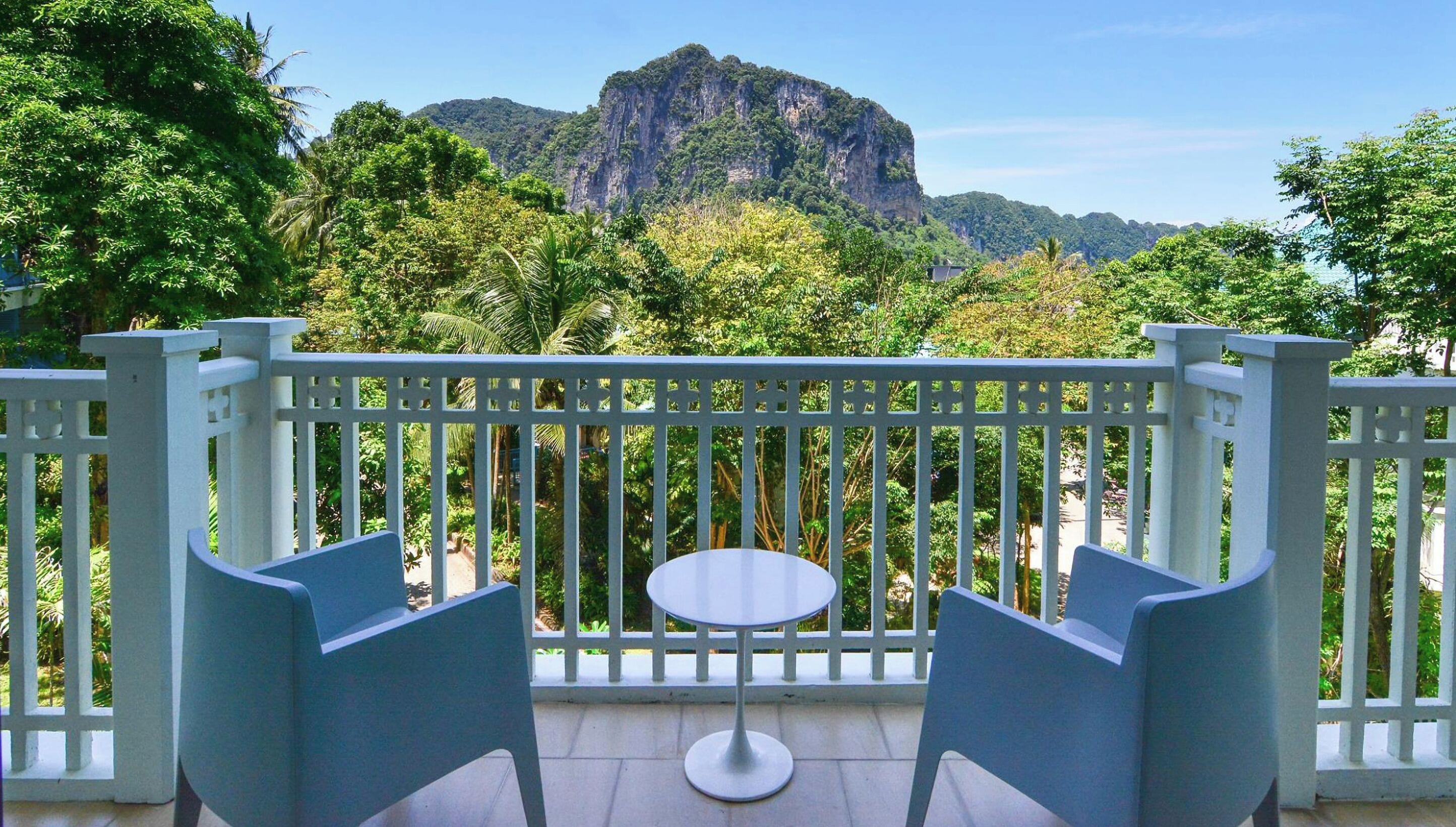 A balcony with two chairs and a small table, overlooking a mountainous landscape.