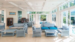Un espacio interior amplio con techo alto, ventanas grandes y diversas opciones de asientos, incluyendo sofás y sillones.
