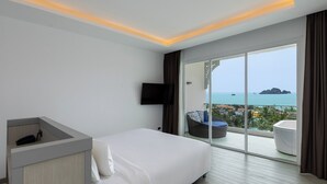 Una habitación de hotel moderna con una cama grande, un escritorio, un televisor de pantalla plana y un balcón con vista al mar.