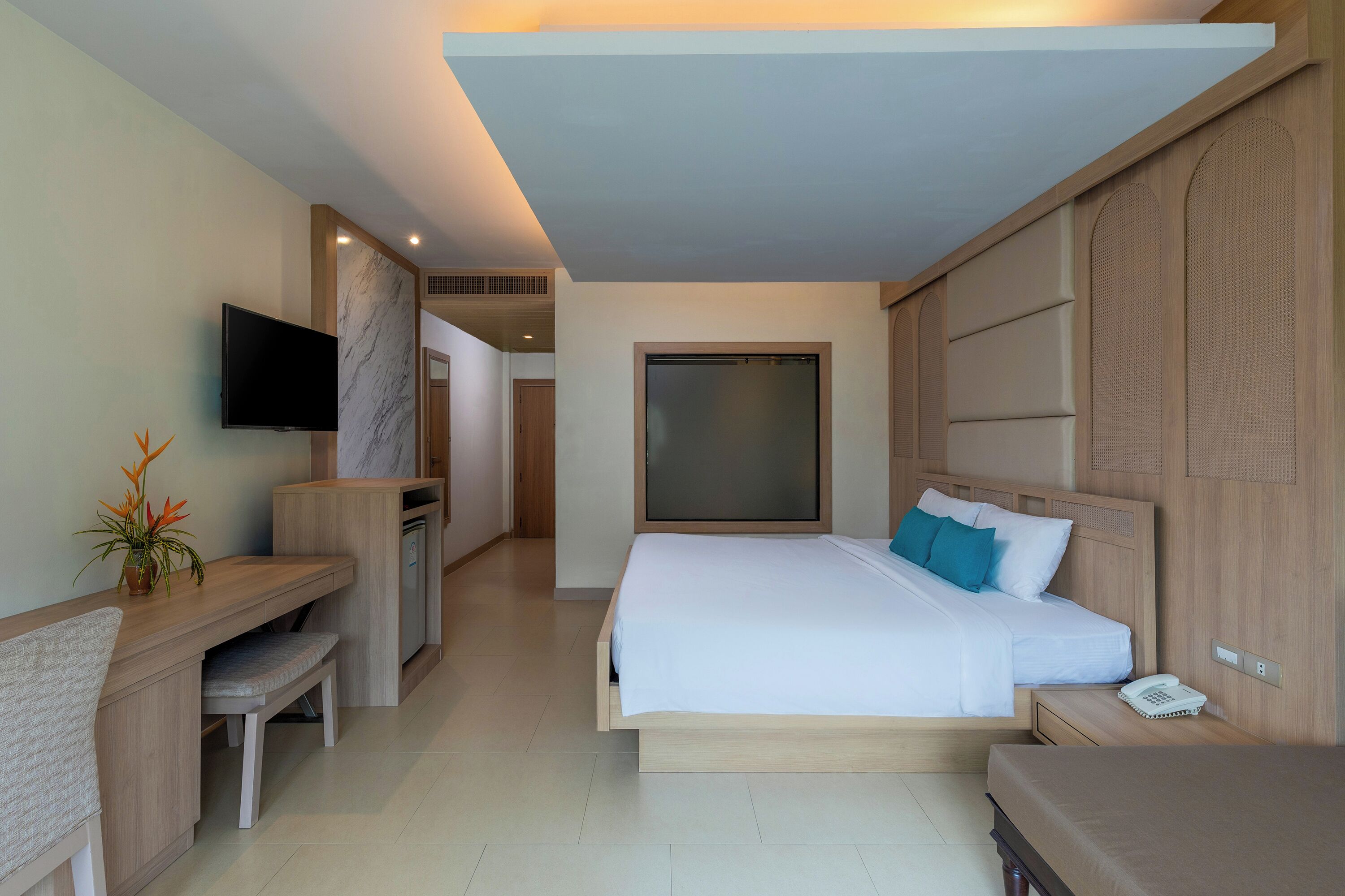 A hotel room with a bed, bedside table, TV, desk, and chair.