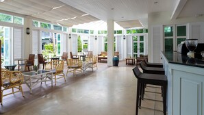 Un espacio interior amplio con muebles de mimbre, una mesa con superficie de vidrio y una encimera de cocina.