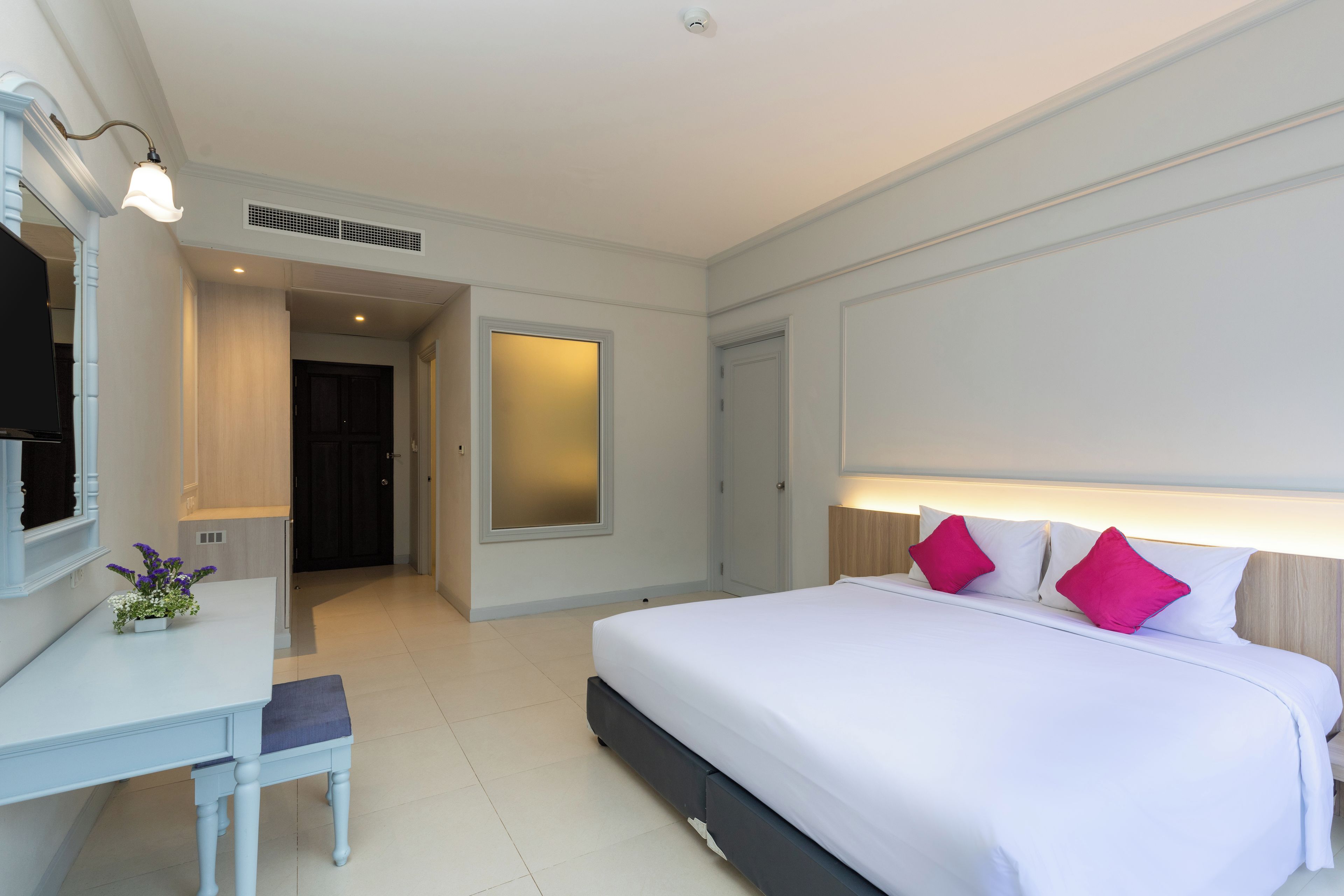 Ein Hotelzimmer mit Bett, Nachttisch und Spiegel.