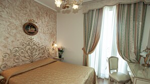 Ein Schlafzimmer mit einem großen Bett, einem Sessel, einer Kommode, einem Spiegel, einer Chandelier und einem Fenster mit Vorhängen.