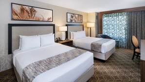 Habitación de hotel con dos camas, un escritorio y una silla.