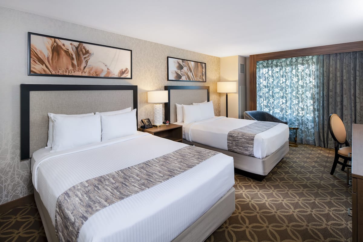 A hotel room with two beds, a desk, and a chair.