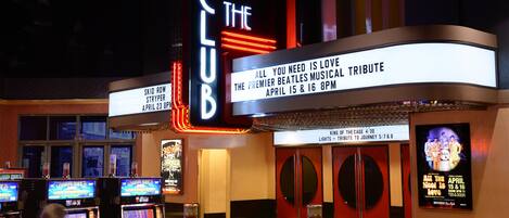 Een locatie met neonborden voor evenementen 'The Club' en 'King of the Cage', met een eerbetoon aan The Beatles en een eerbetoon aan Journey.