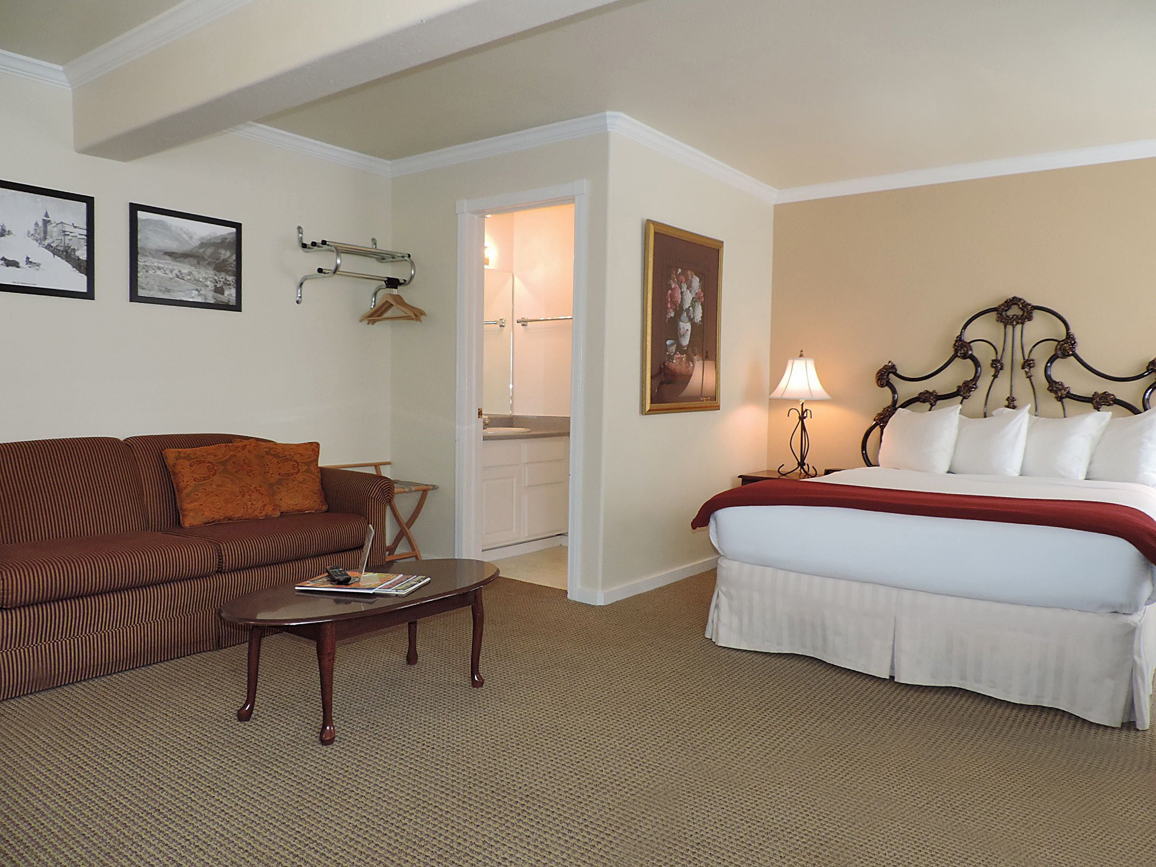 A hotel room with a bed, a sofa, a coffee table, and a bathroom visible through an open door.