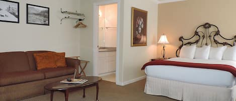 Ein Hotelzimmer mit Bett, Sofa, Couchtisch und einem durchgegangenen Tür sichtbaren Badezimmer.