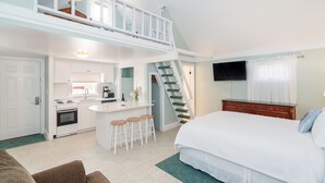 A modern, compact apartment with a kitchen, dining area, and a bedroom with a large bed and a TV. - The Victorian Inn (Telluride)