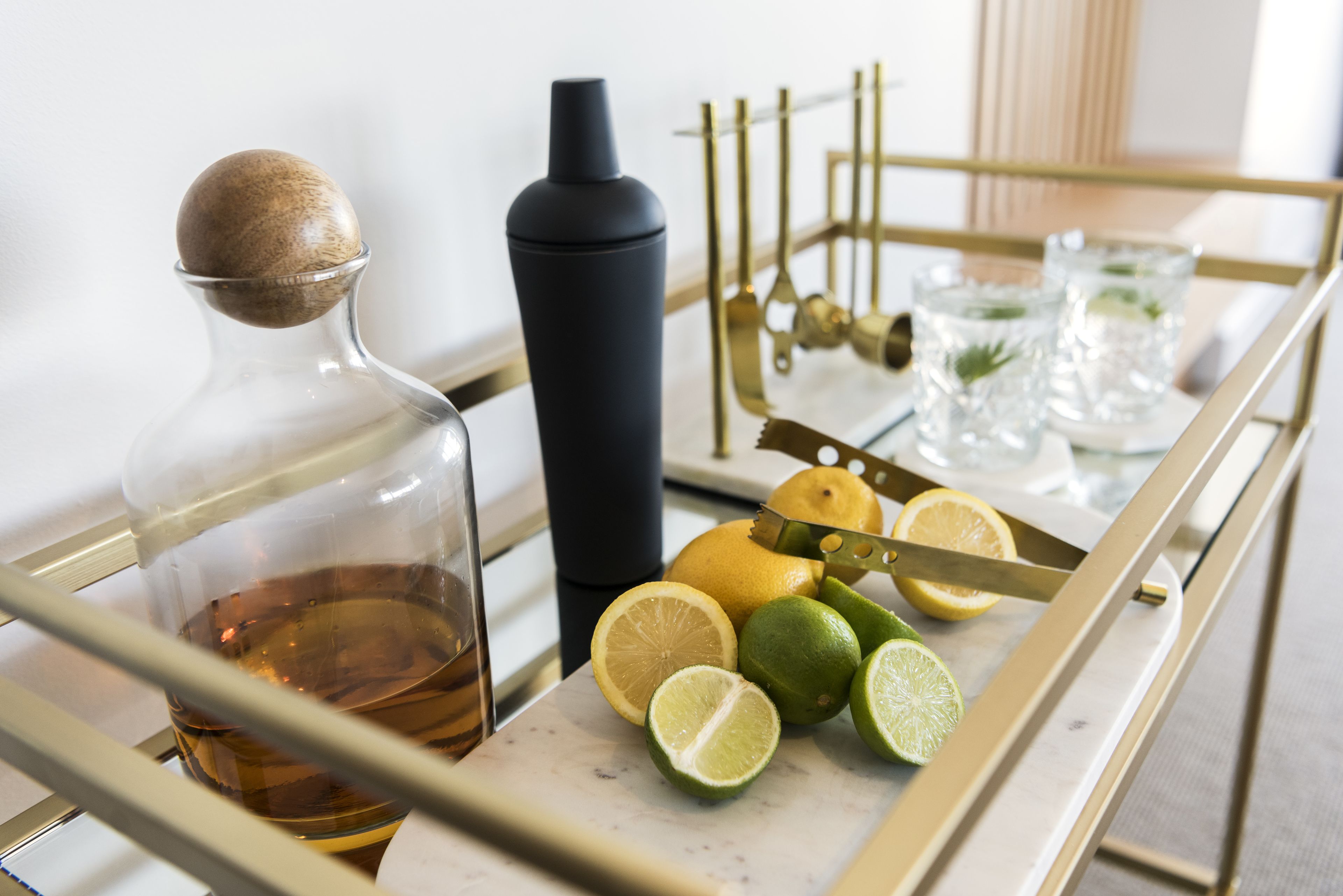 Un comptoir de cuisine avec une bouteille de whisky, un verre à whisky, des citrons, des limes et un couteau.