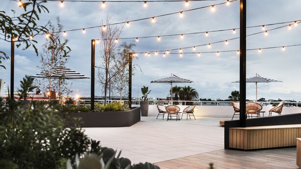 An outdoor patio area with string lights, umbrellas, and seating. - Tradewinds Hotel Fremantle (East Fremantle)