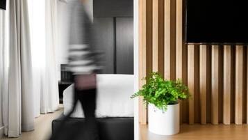 Una sala moderna con un televisor de pantalla plana montado en una pared de paneles de madera, una planta en maceta y un sofá.