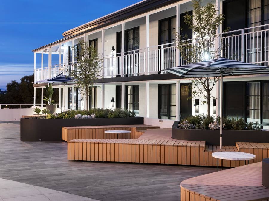 Un hôtel moderne doté d’espaces extérieurs aménagés, d’une terrasse couverte et d’un balcon avec une balustrade.