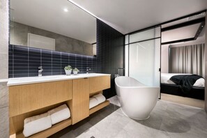 A modern bathroom with a freestanding bathtub, a double vanity with a mirror, and a large window.