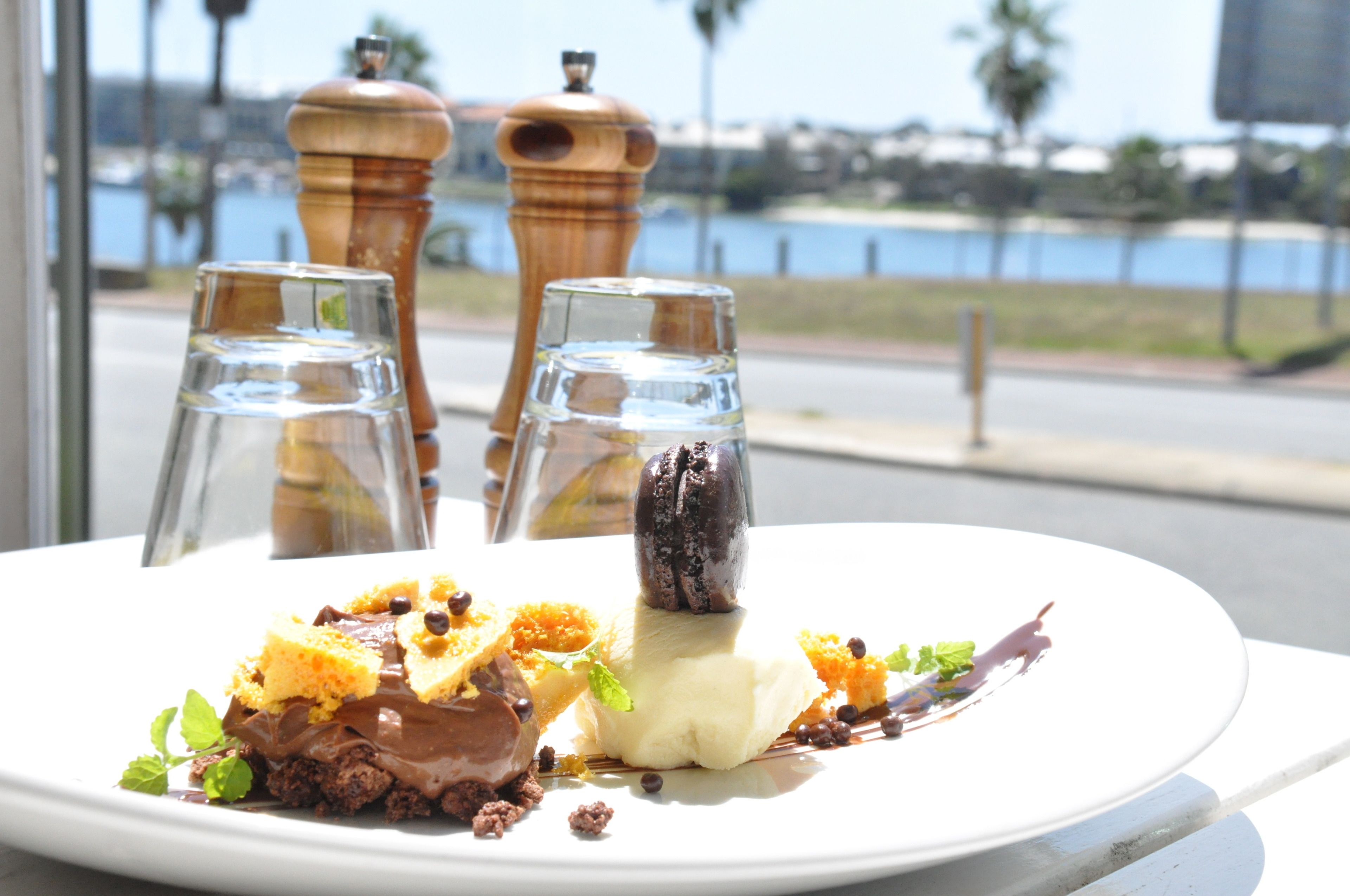 Un plato de postres con diferentes dulces y una vista del frente marítimo al fondo.