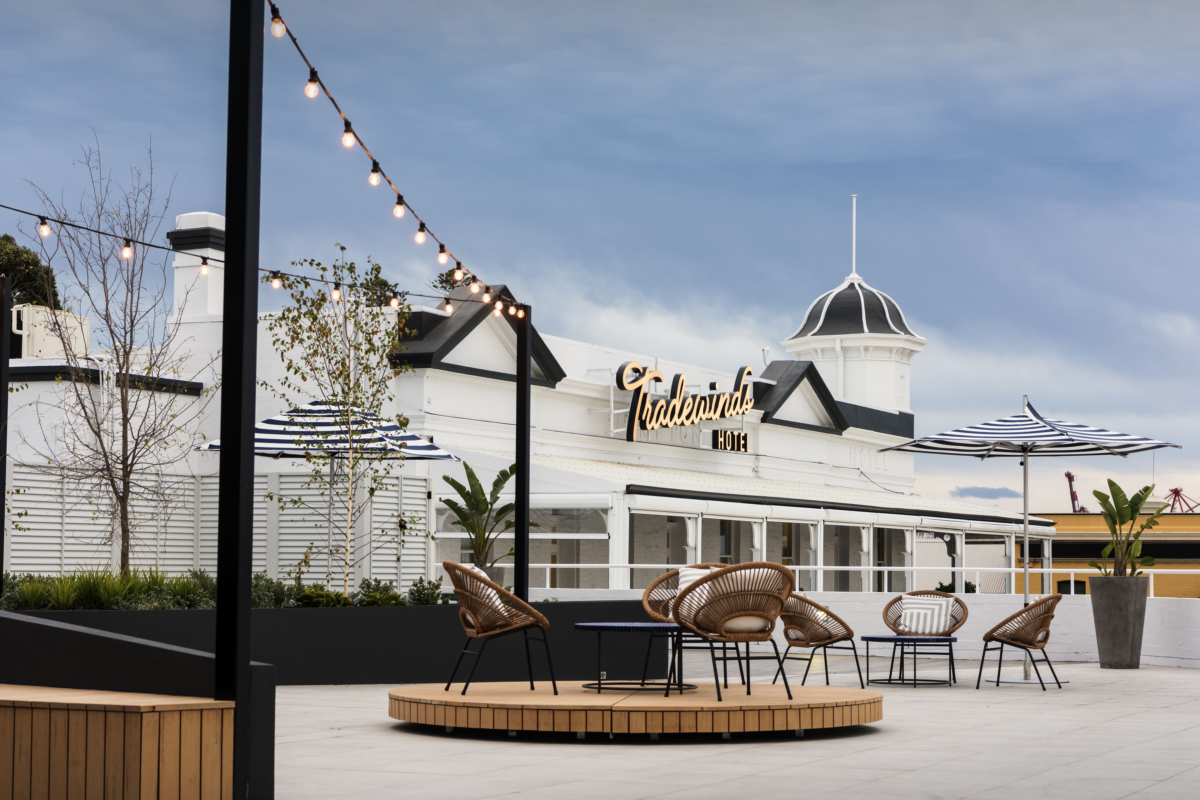 An outdoor seating area with wicker chairs and a table, a sign for 'The Whimsy Hotel', and a large umbrella.