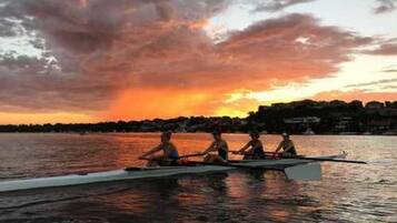 Um pôr do sol sobre a água, com um barco e três pessoas.