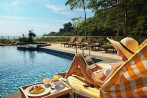 Una piscina al aire libre, sombrillas, sillones reclinables de piscina