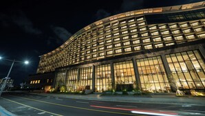 A modern hotel with a curved facade, large windows, and a well-lit entrance.