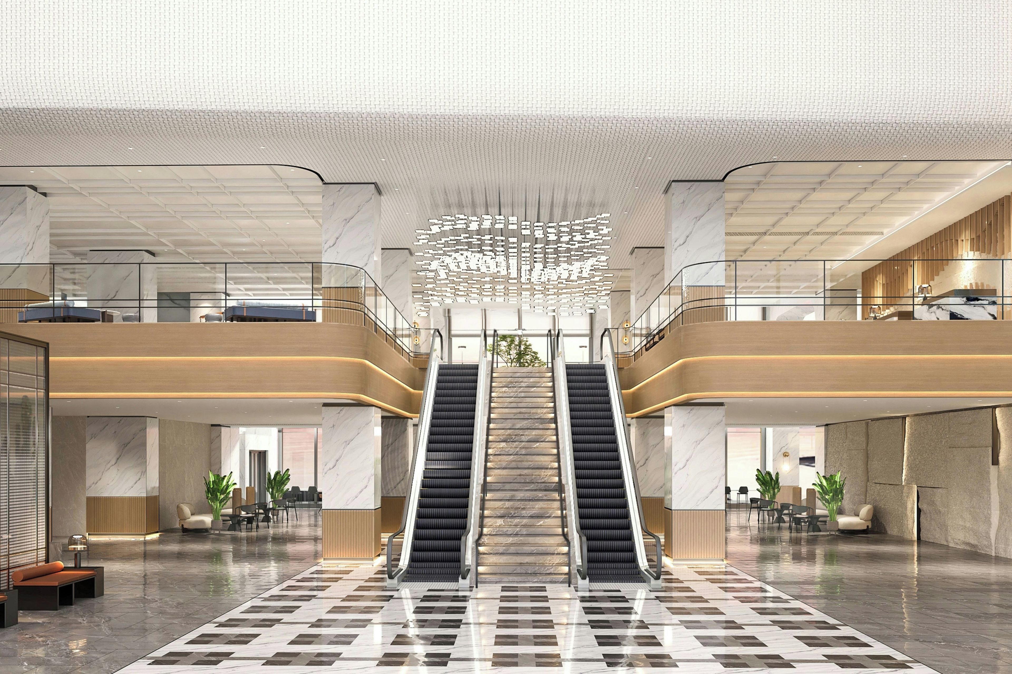 Eine großzügige Lobby mit einer zentralen Rolltreppe, Marmorböden und einem modernen Deckenstil.