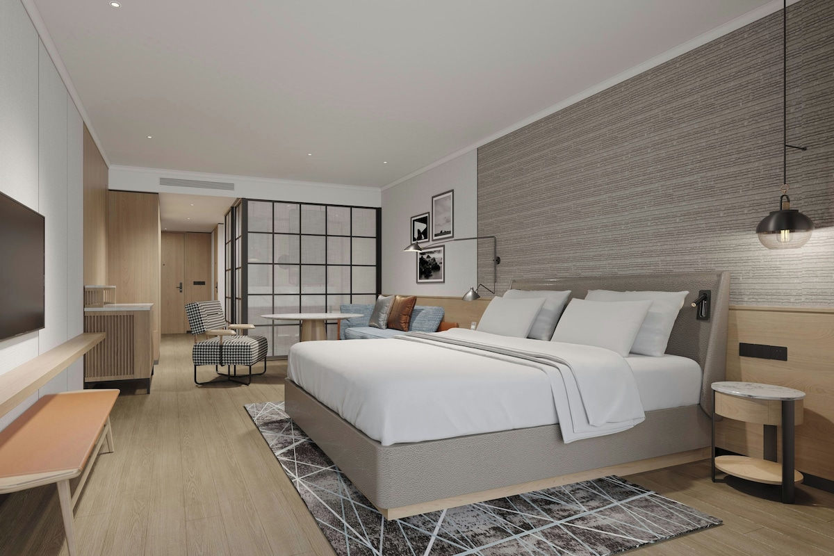 Un dormitorio moderno con una cama grande, mesitas de noche, un escritorio y un televisor.