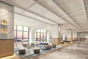 Eine geräumige Lobby mit hoher Decke, Marmorwänden und großen Fenstern mit Blick auf den Sonnenuntergang.