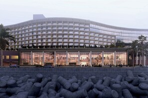 Ein modernes Hotel mit einer geschwungenen Fassade, mehreren Stockwerken und einem großen Glas Eingang.