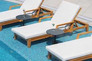 A poolside area with lounge chairs and tables, some with drinks. - Sheraton Jeju (Jeju City)
