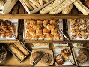 A bakery display with various baked goods including bread, croissants, and pastries. - Novotel Mechelen Centrum (Mechelen)