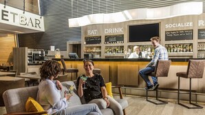 Un espace bar moderne avec des sièges, un comptoir et un barman.