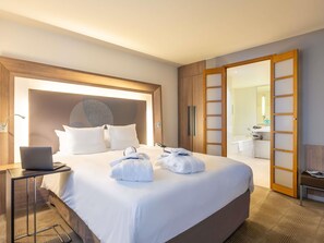 A hotel room with a large bed, a laptop on a bedside table, and a bathroom visible through an open door. - Novotel Mechelen Centrum (Mechelen)