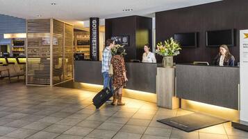 A hotel reception area with a modern design, including a reception desk, seating area, and a bar.