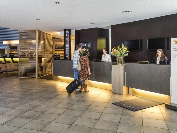A hotel reception area with a modern design, including a reception desk, seating area, and a bar. - Novotel Mechelen Centrum (Mechelen)
