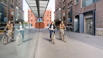 Una calle urbana moderna con ciclistas, edificios de ladrillo y una pasarela cubierta.
