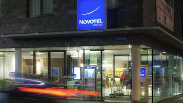 A Novotel hotel with a modern glass facade, a visible reception area, and a clear signboard.