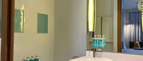 A bathroom with a white sink, a mirror, and a bathtub. There are toiletries on the wall and a towel rack.