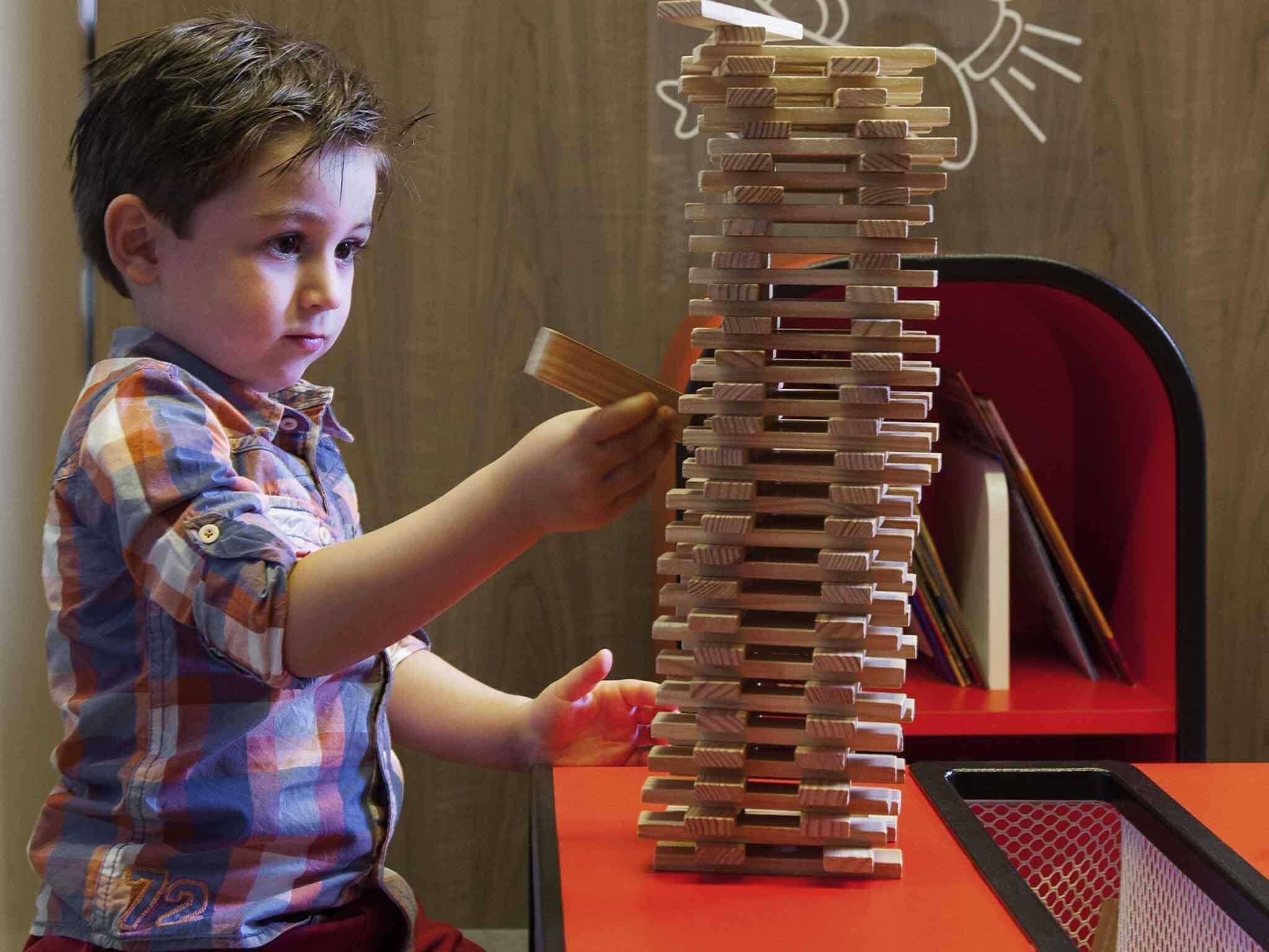 A child playing with a tall wooden structure on a table.