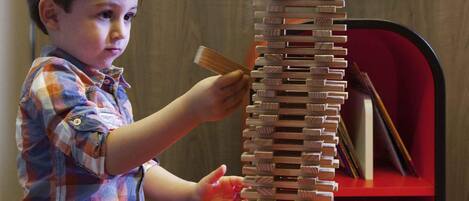 A child playing with a tall wooden structure on a table.